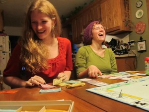 Two girls laugh while playing a board game