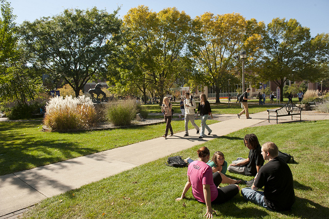 Students walk across campus and relax on the grass