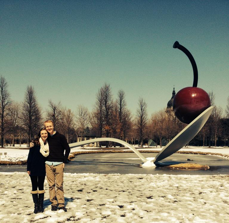 a couple stand in front of an outdoor sculpture