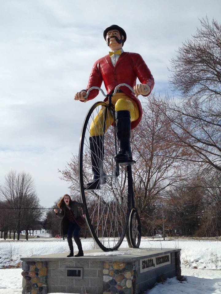 Olivia poses next to a giant statue of a bicyclist