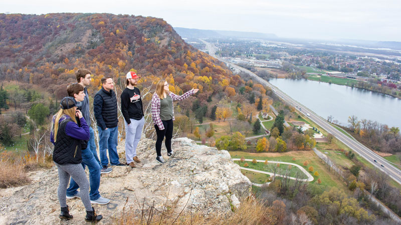 WSU students stand on a ledge in the bluffs looking out over Winona