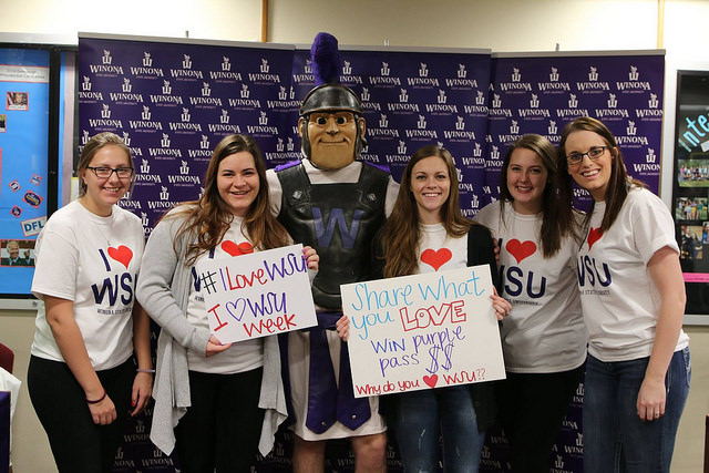 Wazoo poses with female students holding signs