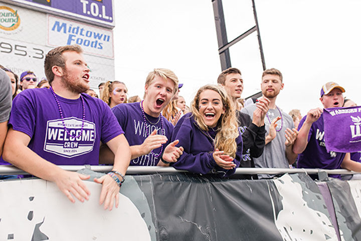 Students cheering in the student section at the football game.