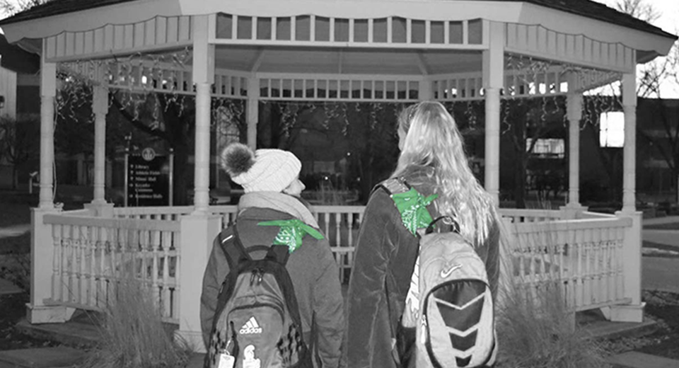 Green Bandana Project starters standing in front of the gazebo showing off their bandanas on their backpacks. 