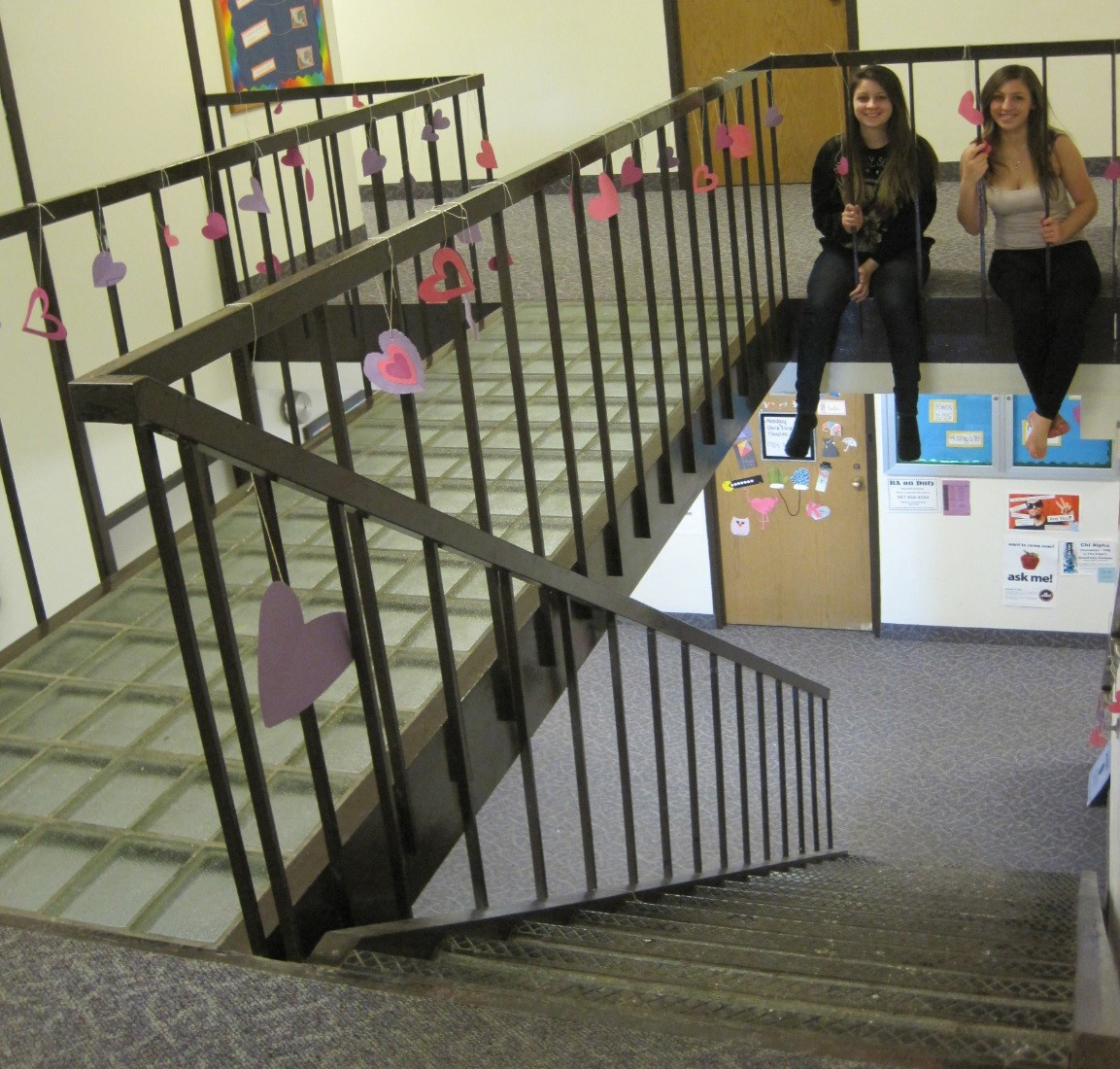 Two girls sit on a stairway landing