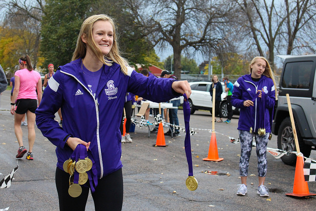 Student hands out medals at the finish line of the Warrior Waddle 5K