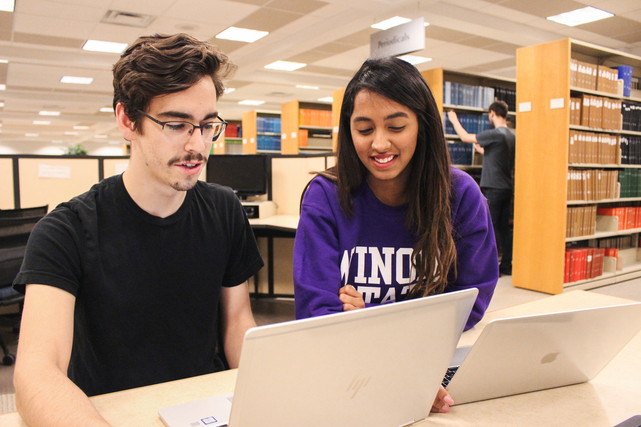 Two WSU students working together on their laptops.