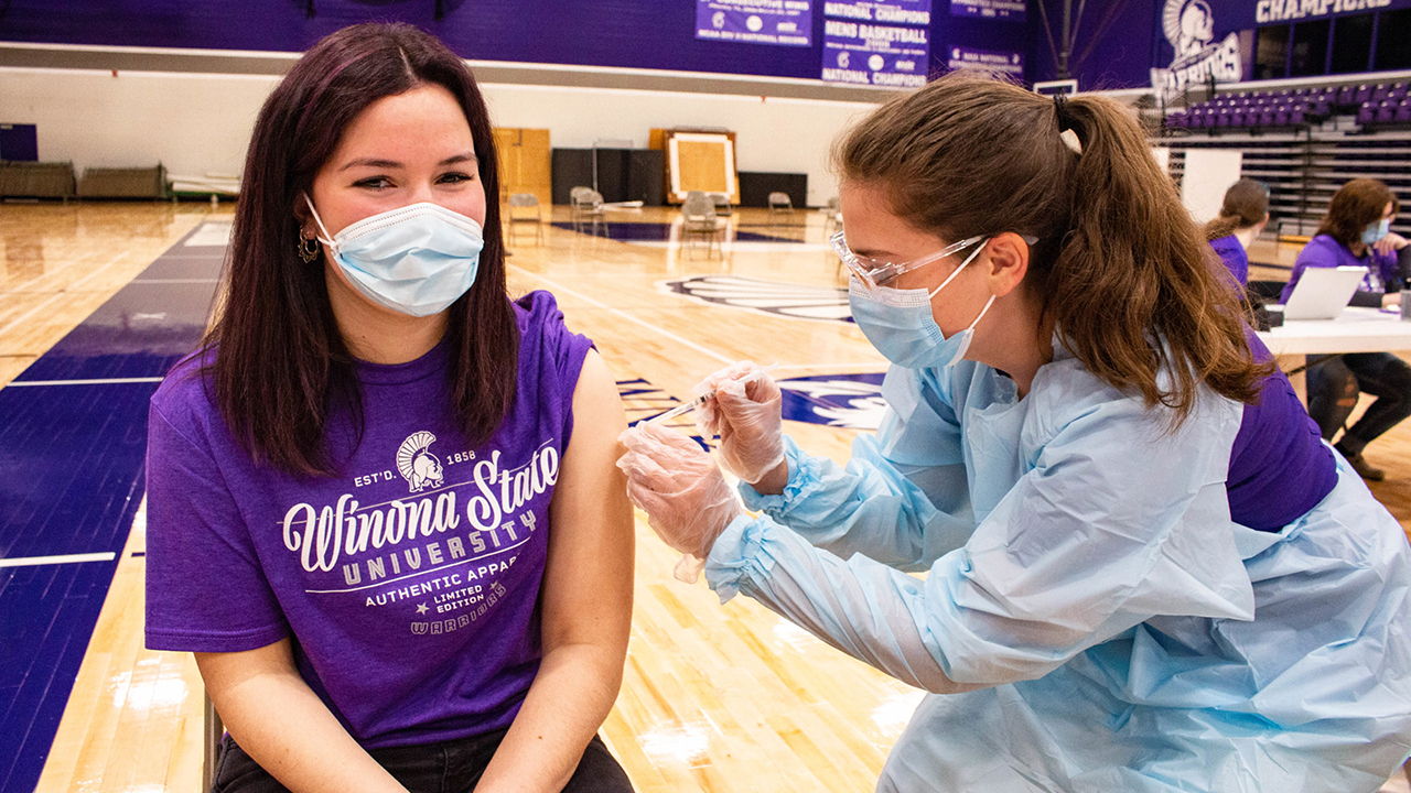 A student recieves a vaccine from a volunteer in the McCown Gym.