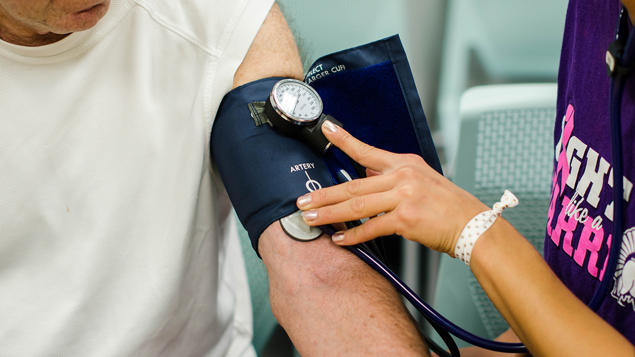 A WSU student measures a community member's blood pressure.